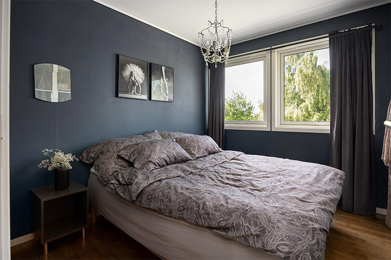 Modern bedroom with a bed and pillows near a large window providing natural light